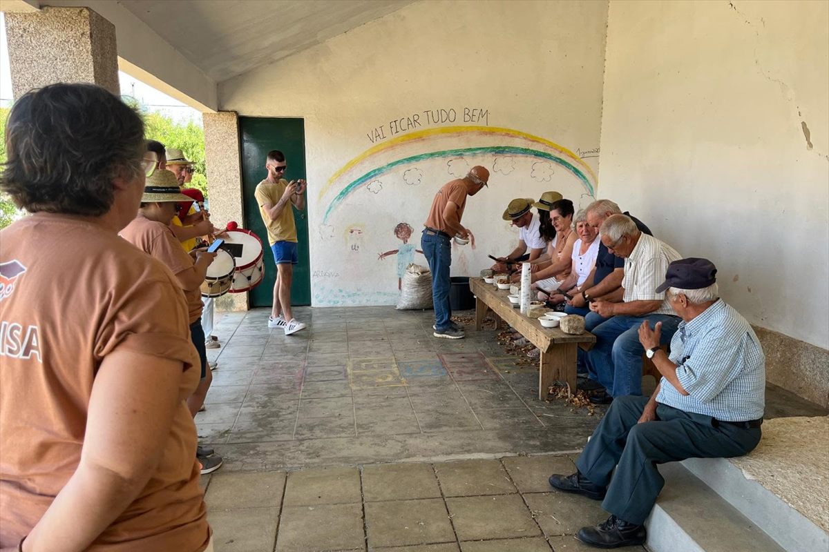 Participantes sentados num banco a partir amêndoa, ao lado de músicos com bombos