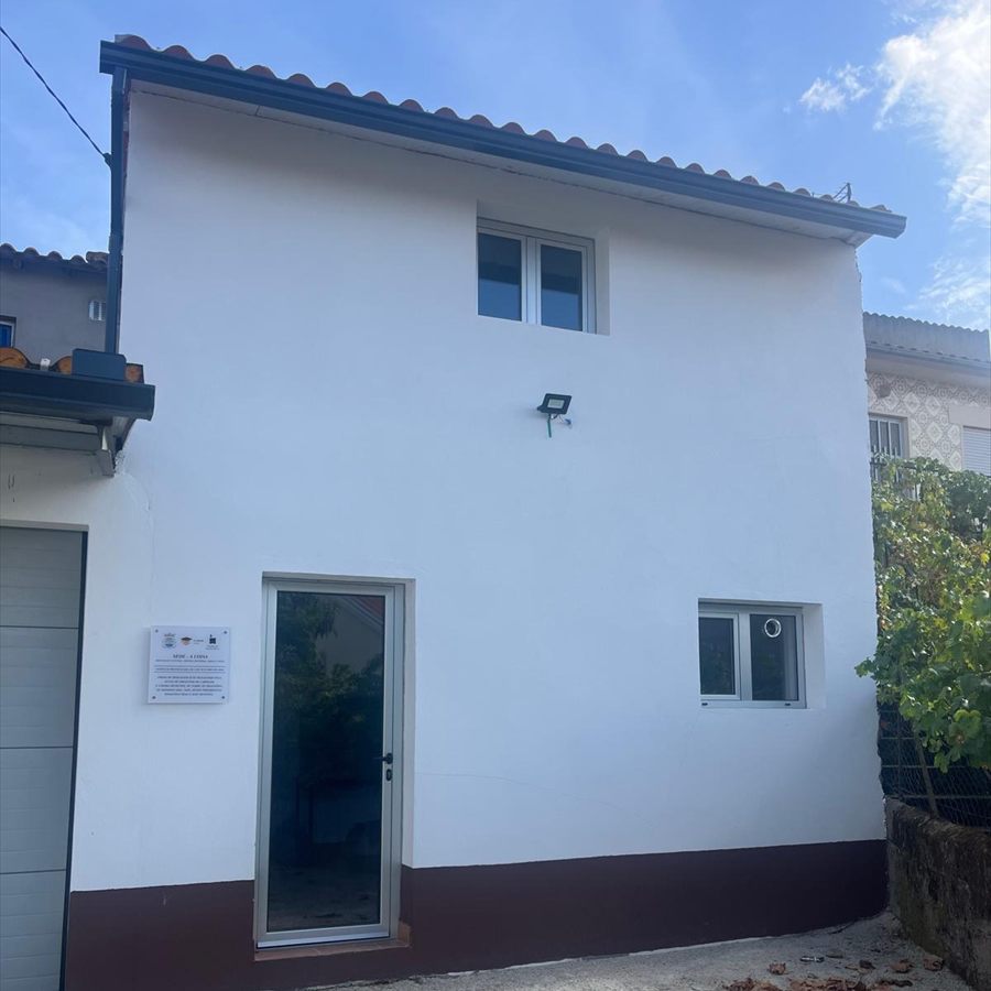 Empena do edifício da antiga moagem, sede da A COISA, com a placa de identificação junto à porta de entrada