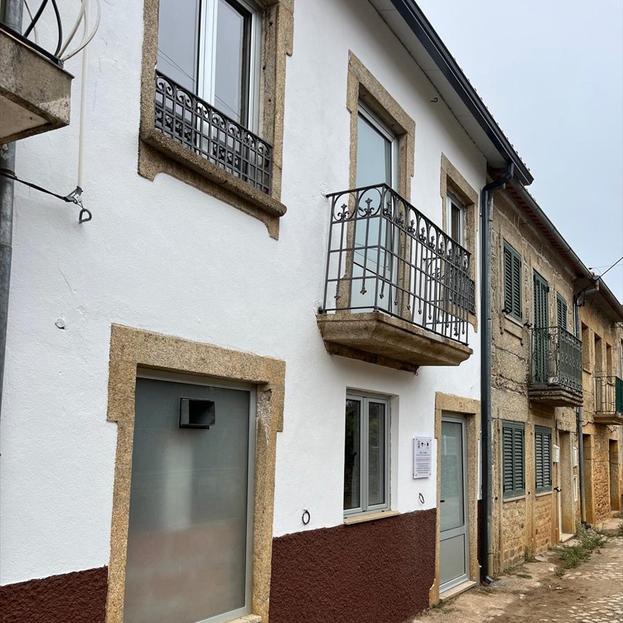 Fachada da sede virada à rua de calçada, com janelas de moldura em granito e varanda de ferro forjado